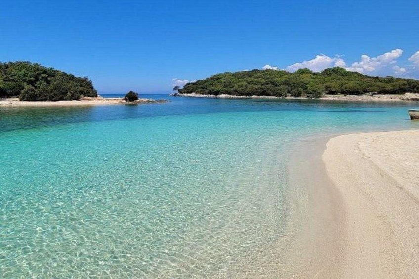 A clear turquoise sea, sandy beach, and lush green islands. 1