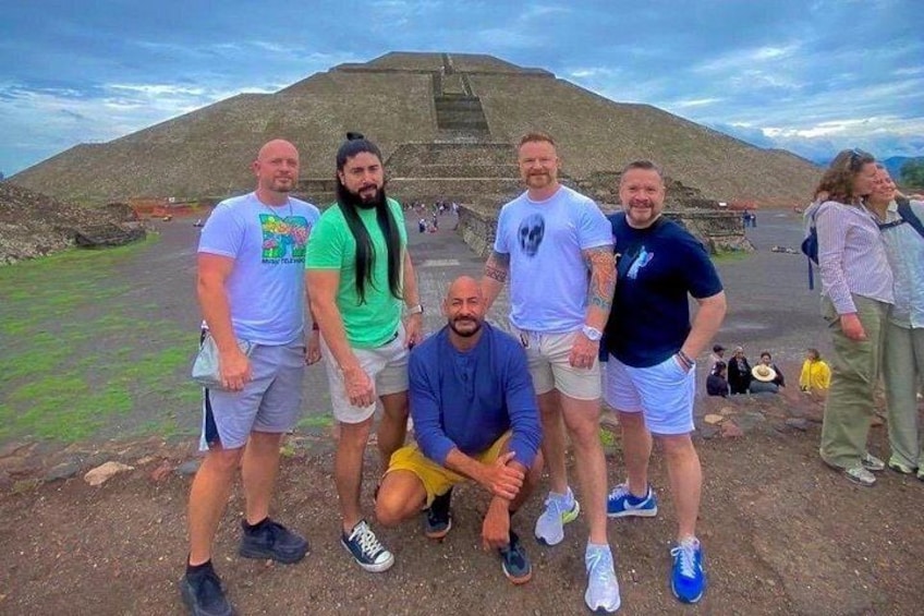En gruppe mennesker står foran en pyramideformet bygning med en trappe op ad den. 1