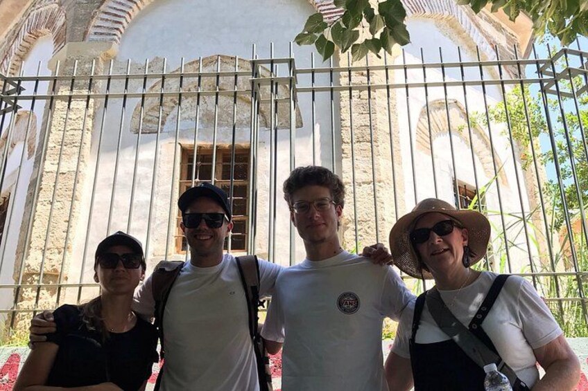 Four people standing in front of a historic building with arches and columns. 1