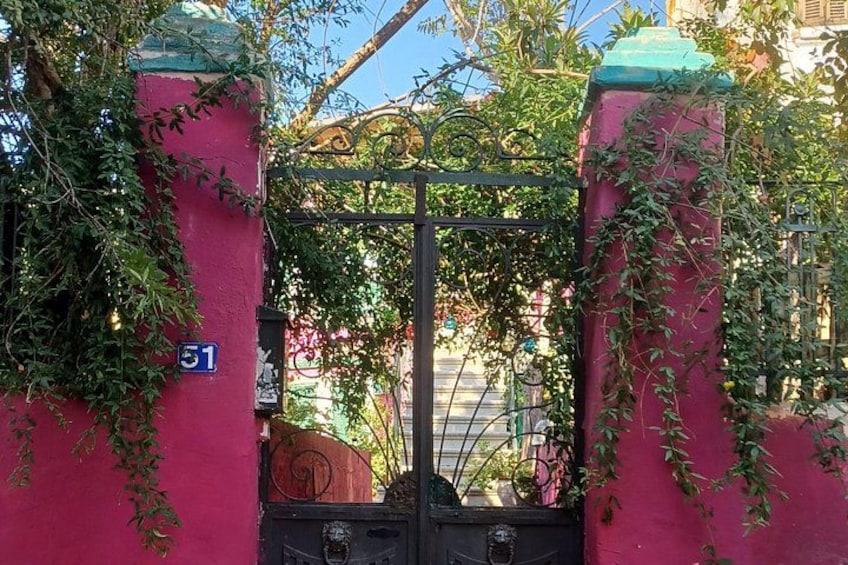 A gated entrance with a number sign, a metal gate, and a red wall with greenery. 2