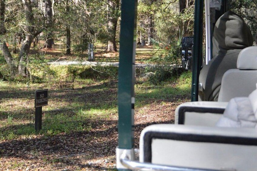 A bus with a 'No Parking' sign in a wooded area. 2