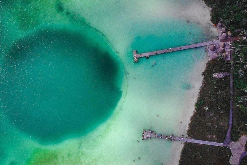 A turquoise lagoon with a pier extending into it. 3