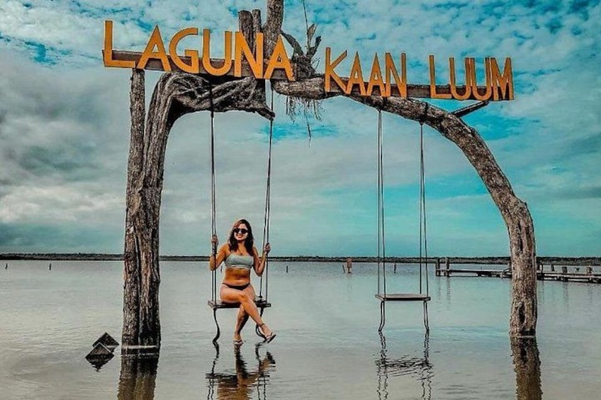 A woman on a swing made from tree branches with the text 'LAGUNA KAAAN LUUM' above. 4