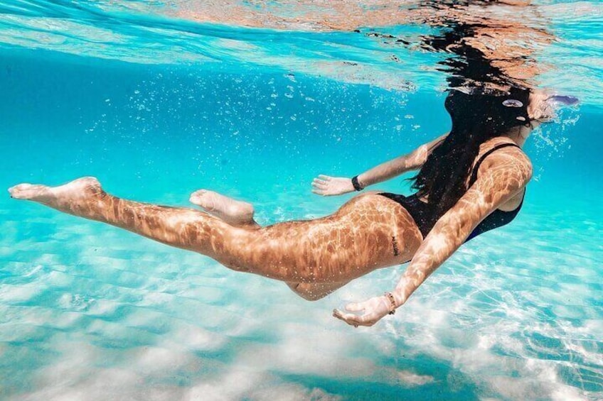 A person swimming underwater in clear blue water. 1