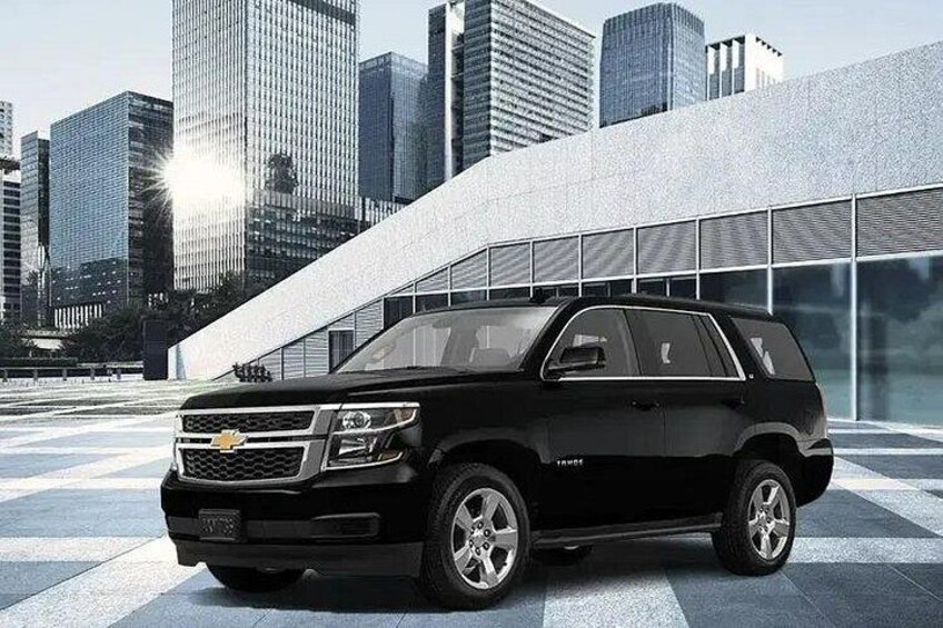 A black Chevrolet SUV parked in front of a modern building with a glass facade. 3