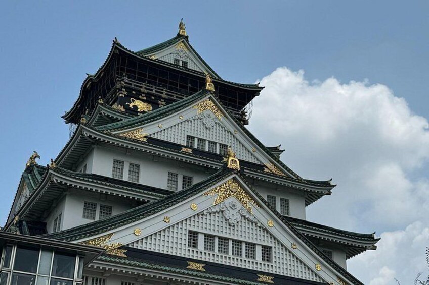 A traditional Japanese castle with multiple tiers, ornate golden decorations, and a clear sky in the background. 2