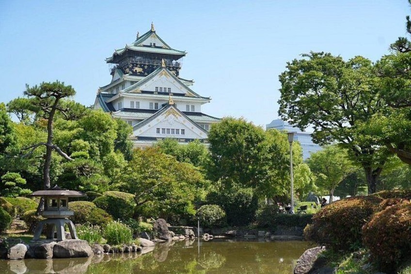 A traditional Japanese castle with a pond and trees in the foreground. 4
