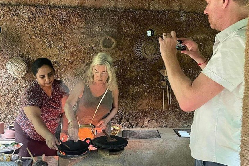 Three people cooking outdoors with a rustic stone wall in the background. 2