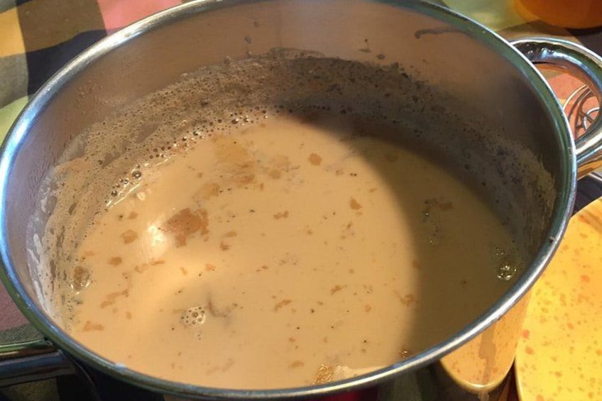 Une casserole en acier inoxydable contenant un liquide crémeux, peut-être une soupe ou une sauce, posée sur une cuisinière. 3