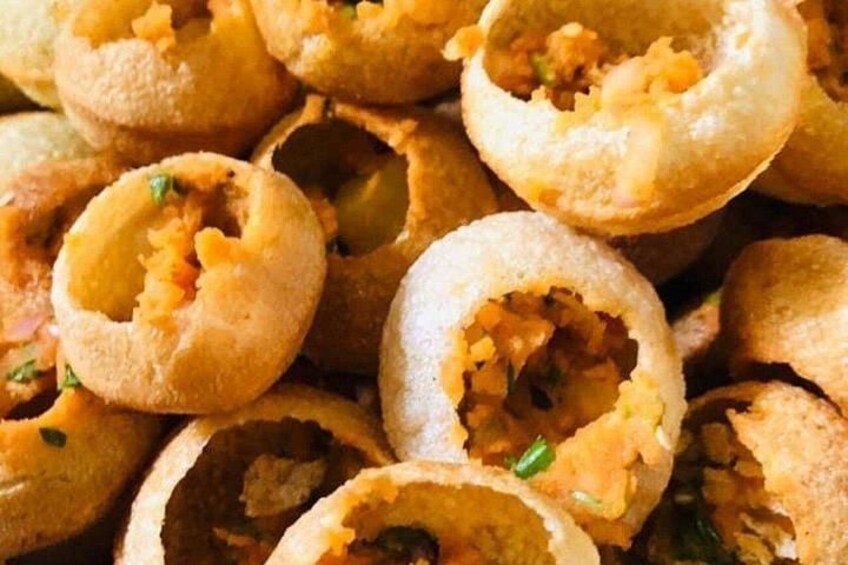 Gros plan sur des aliments frits, probablement des beignets ou des amuse-gueules, avec des herbes visibles et une croûte dorée. 2