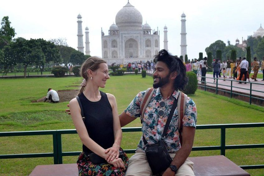Two people sitting on a bench with the Taj Mahal in the background. 2