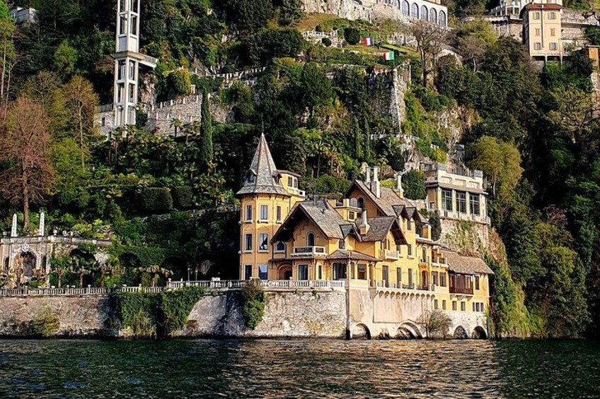 A historic building with a tower, situated on a hillside overlooking a body of water. 4