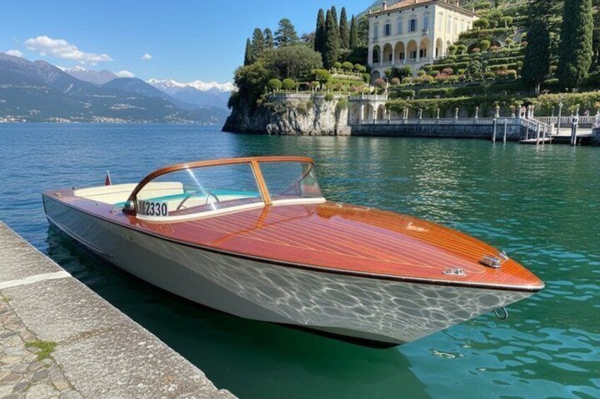 A speedboat docked at a pier with a mountainous backdrop and a grand building. 1