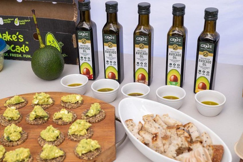 Flesjes avocado-olie, een doos, een houten plank met avocado-toast en een bord gegrilde kip. 2