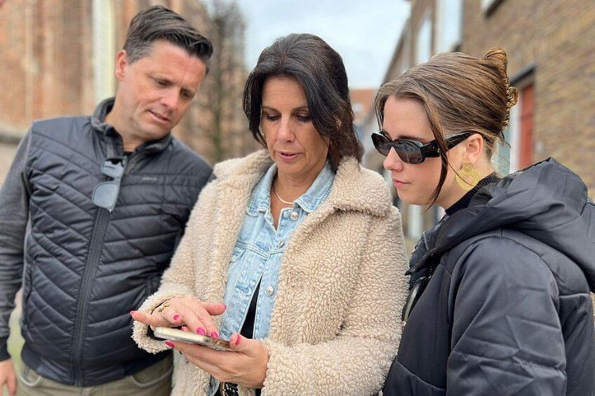 Three people standing outdoors, one holding a smartphone. 2