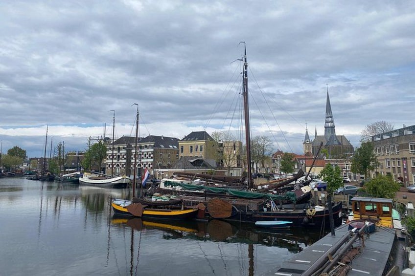 A harbor with boats, a church spire, and buildings along the waterfront. 3