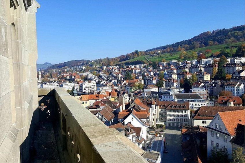 A cityscape with a prominent building on the left, a river in the center, and a hilly landscape in the background. 3