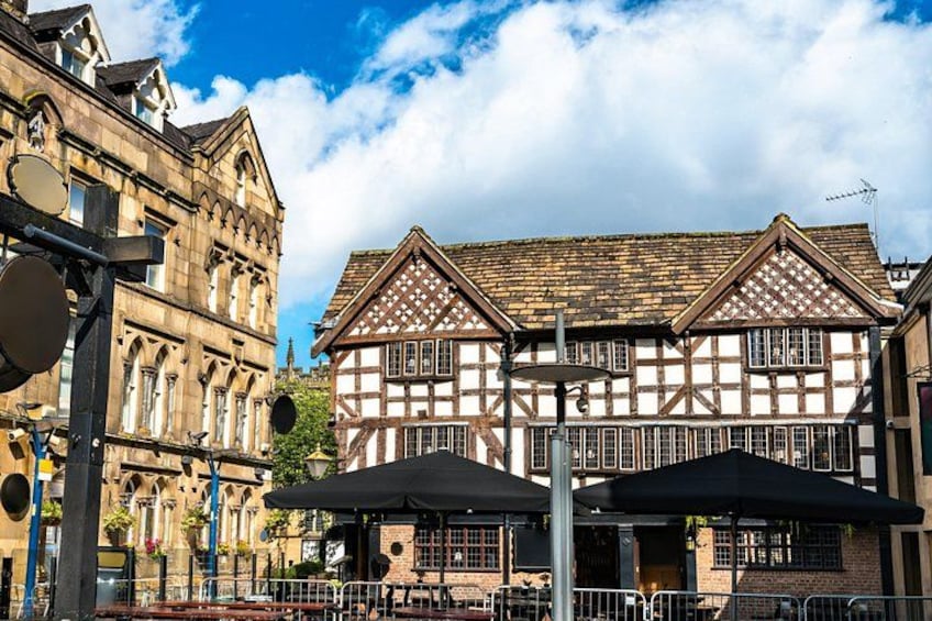 A traditional half-timbered building with a tiled roof, surrounded by modern street furniture and a clear blue sky. 5