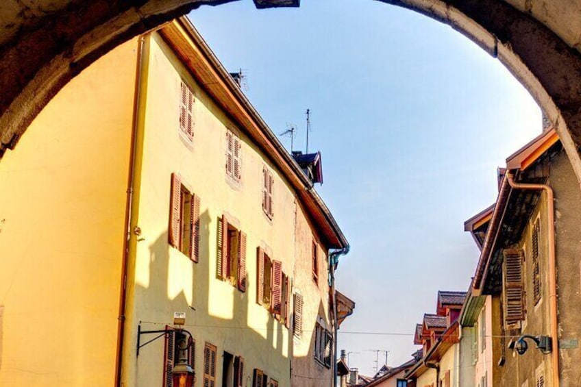 A narrow street with buildings, an archway, and a clear sky. 4