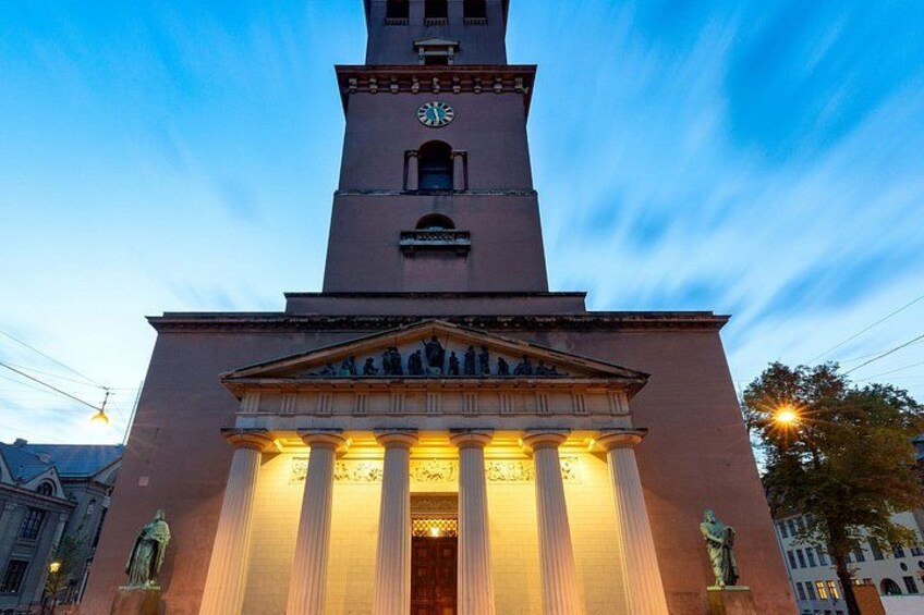 A clock tower with a classical facade, columns, and a statue at the base. 4