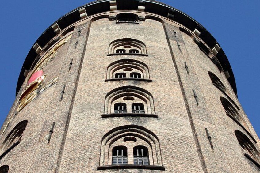 A tall, cylindrical brick tower with arched windows and a circular top. 3