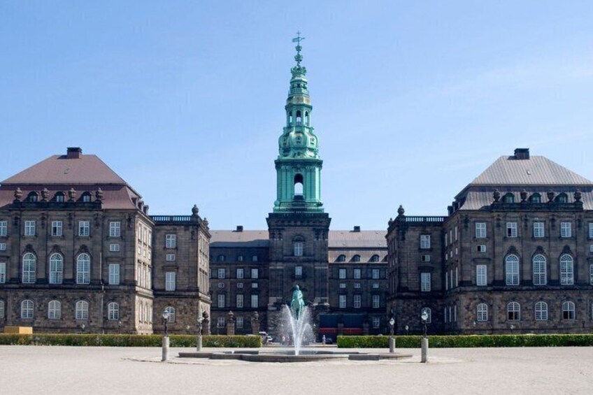 A historic building with a prominent tower and a fountain in the foreground. 5