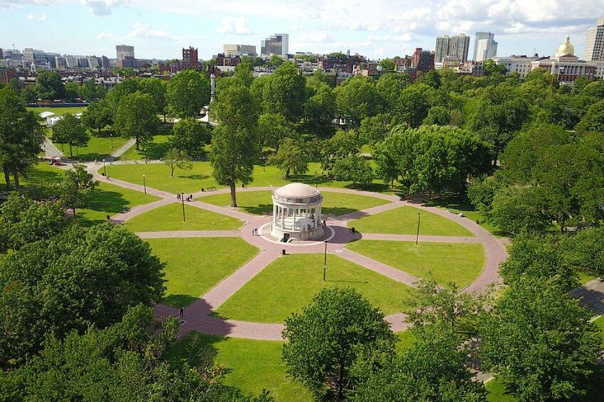 A park with a central gazebo, pathways, and surrounding greenery. 2