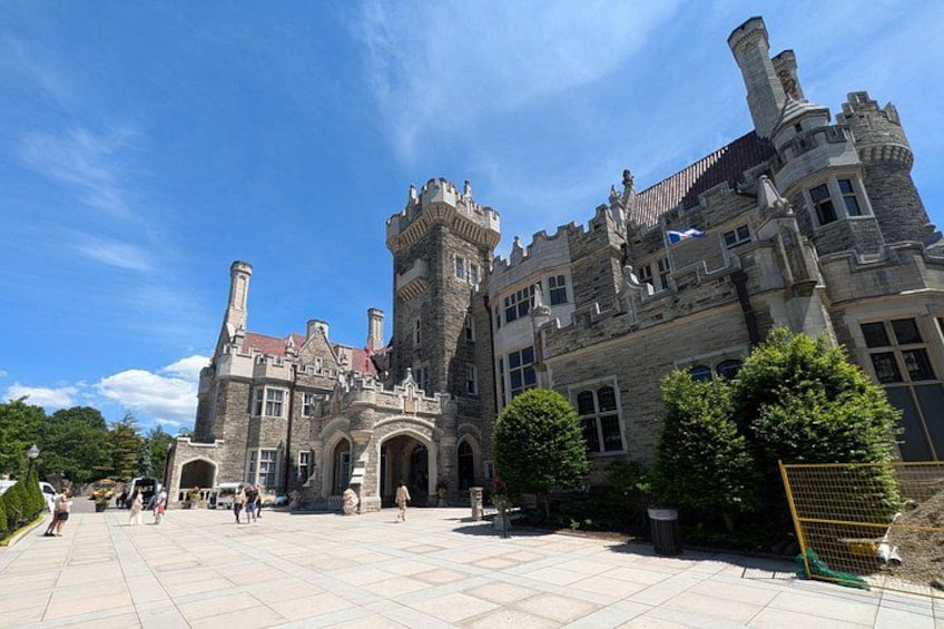 A large, historic stone building with a prominent tower and arched entrance. 1