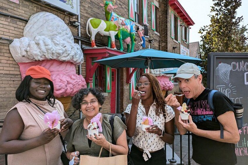 People enjoying ice cream at an outdoor food stall with a large ice cream cone decoration and a cow statue. 2