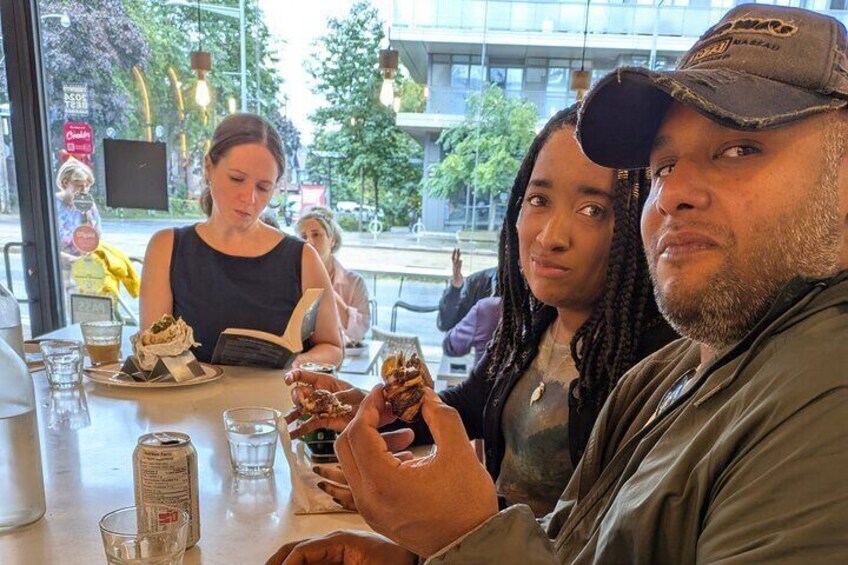 People sitting at a table in a cafe, with food and drinks in front of them. 2