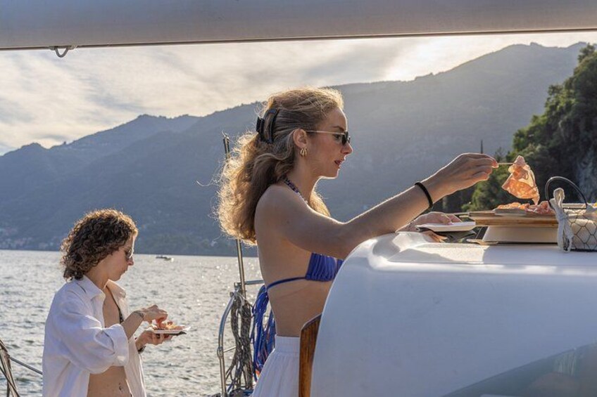 Twee personen dineren op een boot, met een bergachtig landschap op de achtergrond. 5