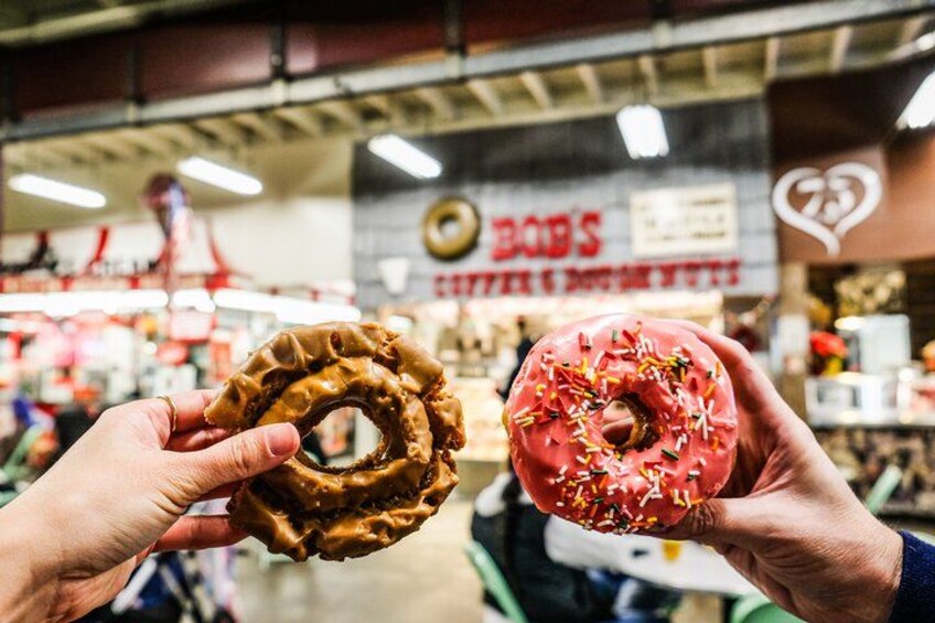 Dos personas sosteniendo donas en una panadería. 1