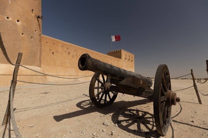 A cannon in a desert setting with a flag in the background. 2