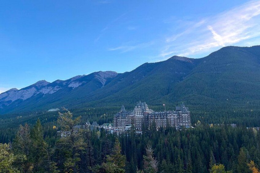 A large, historic building surrounded by dense forest and mountains. 5
