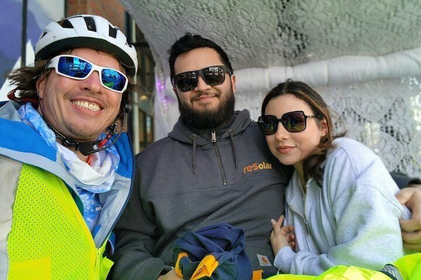 Tres personas con equipo de ciclismo, una con casco, y una estructura de encaje al fondo. 5