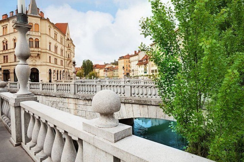 A stone bridge with balustrades, a river, and buildings in the background. 4