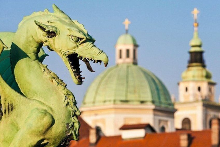 A green dragon statue in front of a building with a green dome and a smaller dome with a cross on top. 5