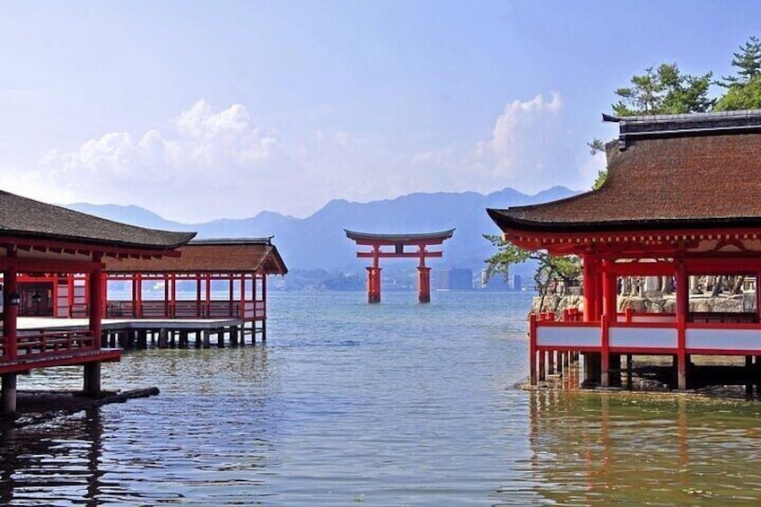 Un torii japonés tradicional en el agua, rodeado de edificios rojos. 3