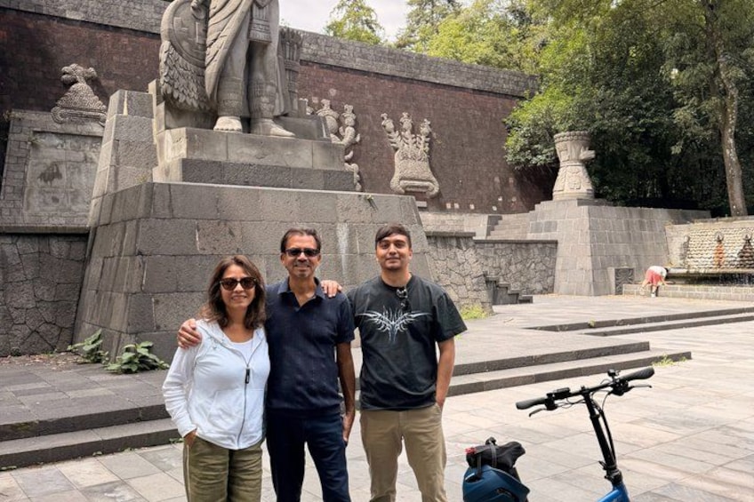 A group of people standing in front of a large stone monument with statues and inscriptions. 3