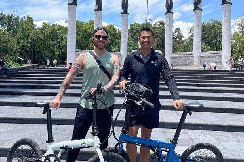 Two people standing in front of a set of steps with bicycles. 1