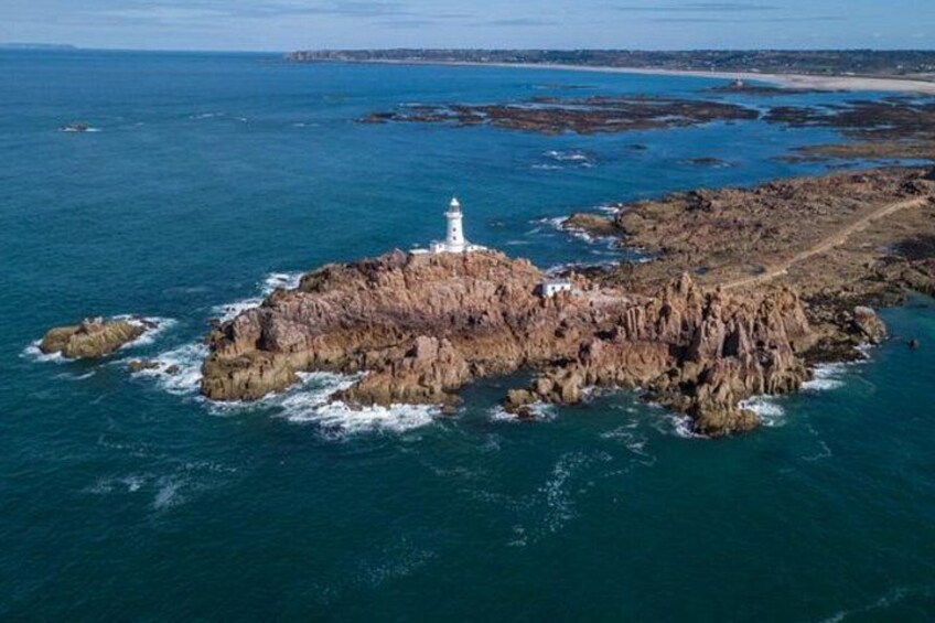 A rocky island with a lighthouse, surrounded by deep blue sea. 5