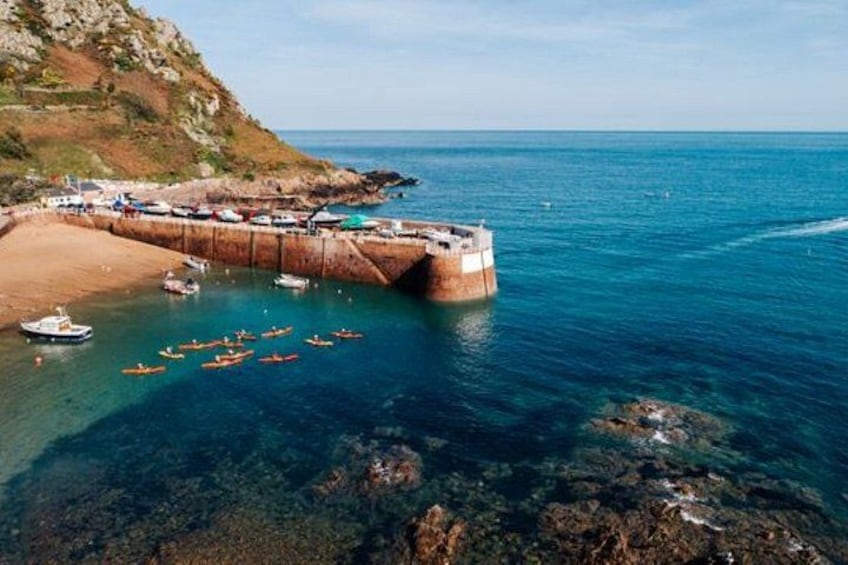 A coastal area with boats, a sandy beach, and rocky terrain. 2