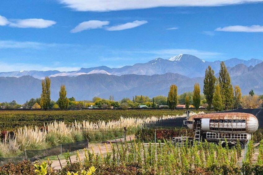 A rural landscape with mountains, a field, and a rusted structure. 1