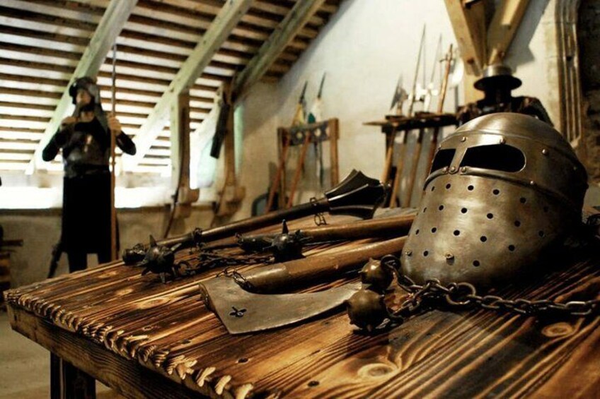 A wooden table with medieval armor and weapons, including a helmet and a sword. 3