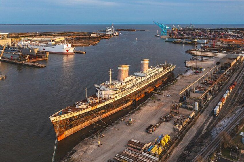 A large cargo ship docked at a port with cranes and industrial buildings in the background. 4