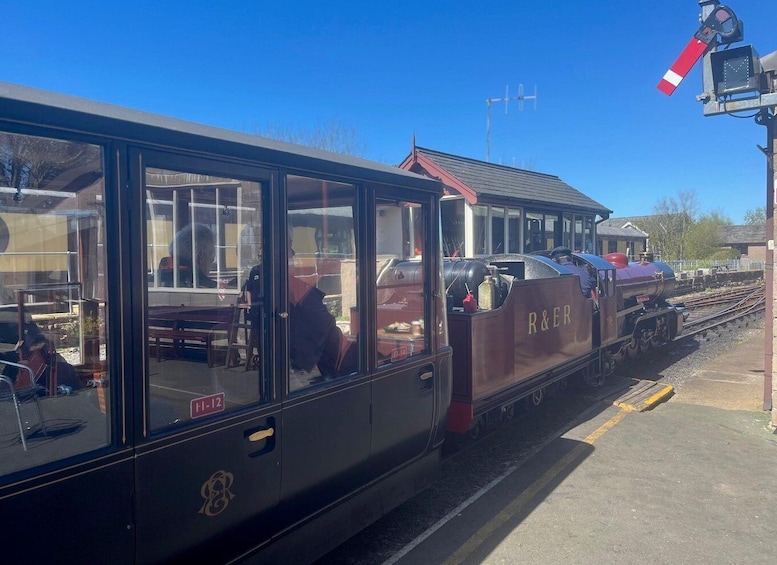 A vintage train with 'R&ER' on the side, parked at a station with a clear blue sky. 2