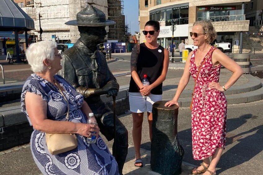 Une statue représentant un soldat, une femme portant une robe à motifs floraux et un homme vêtu d’un t-shirt et d’un short noirs. 1