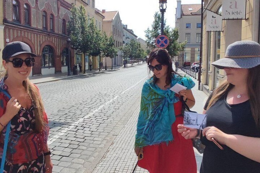 Three women standing on a cobblestone street, one holding a map. 2