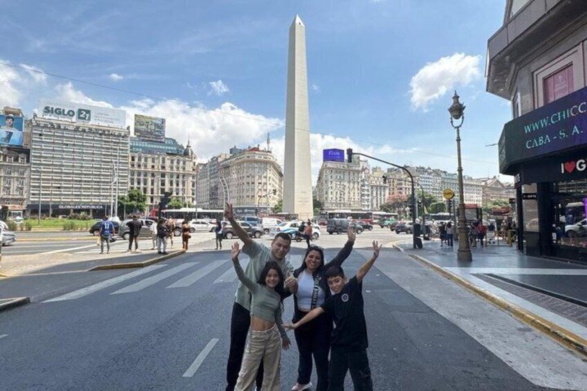 Un grupo de personas posando frente a un monumento, con un paisaje urbano de fondo. 2