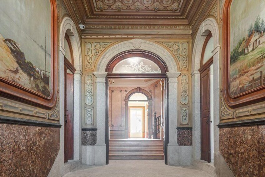 An ornate hallway with marble flooring, decorative columns, and frescoes on the walls. 5